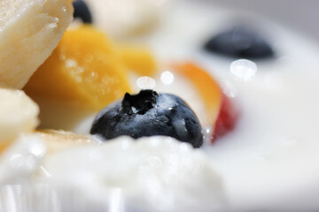 White yogurt with fresh fruit - peach, mango, blueberries, bananas macro shot. Delicious healthy sour milk product for a healthy breakfast. Dairy products abstract background. Diet healthy food.