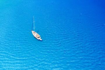 Aerial view of the yacht on the blue sea. Transparent water in the Mediterranean Sea. Summer vacations and travels on a sailing yacht. Summer relaxation.