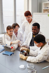 Vertical portrait of African American teacher demonstrating science experiments to group of...