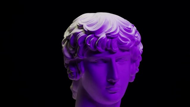 Plaster head sculpture Apollonian in purple neon light close-up. Gypsum ancient statue isolated on black background.