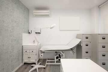 Table with a paper cover in a beauty clinic with gray filing cabinets and a magnifying lamp