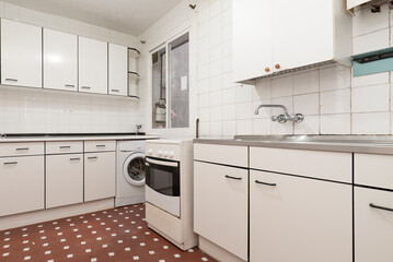 Kitchen with drawer furniture in white tones with details and edges in black with a metal kitchen, stainless steel sink and white square tiles with a clay terrazzo floor with white touches