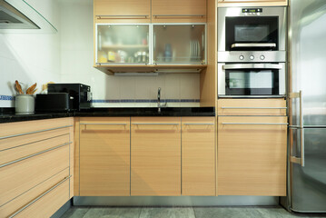 kitchen with wooden furniture and matching drawers with black stone countertop and stainless steel...
