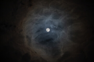 Obraz na płótnie Canvas Full moon behind clouds on a dark sky