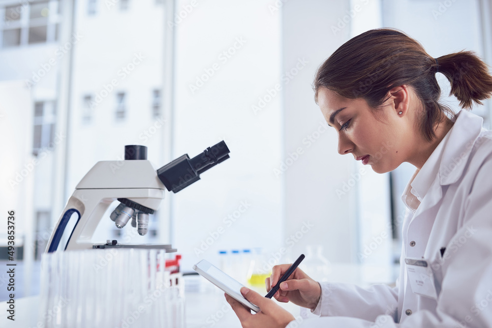 Aufkleber Research is only one part of the job. Shot of a focused young female scientist working on a digital tablet while being seated inside of a laboratory.