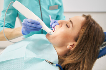 Dentist examining female teeth with dental 3D scanner - obrazy, fototapety, plakaty