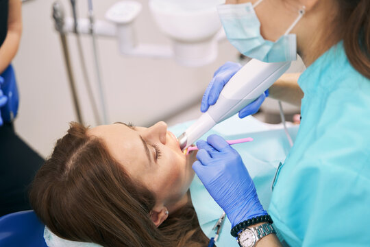 Dentist examining woman teeth with dental 3D scanner
