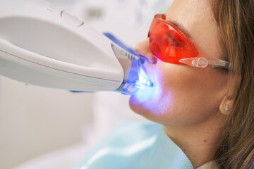 Woman having laser teeth whitening procedure in stomatology clinic