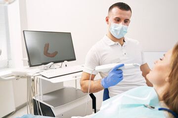 Male dentist examining woman teeth with 3D dental scanner - obrazy, fototapety, plakaty