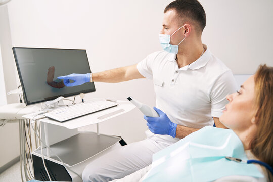 Male doctor showing results of dental 3D scanning to woman in clinic