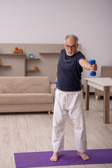 Fototapeta na wymiar Old man doing sport exercises at home