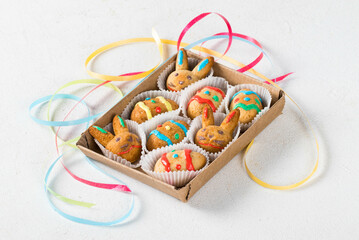 Easter cookies in the shape of eggs and rabbits, decorated with colorful icing sugar, in a serving box. Light background