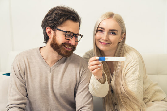 Excited young Caucasian couple woman showing a positive pregnancy test to the camera portrait . High quality photo