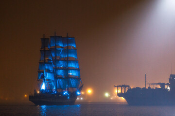 A beautiful sailing ship passes under the glowing Golden Bridge in Vladivostok. Training sailboat...