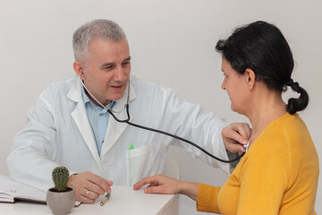 Doctor listening to chest of female patient during medical exam in office