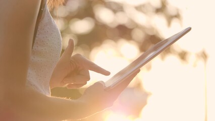 tablet close-up. girl hands press finger display tablet sunset. modern human happiness. remote work...