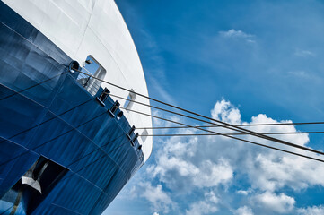 The cruise ship docked at the port with ropes on sky background, mooring a vessel or ship with a...