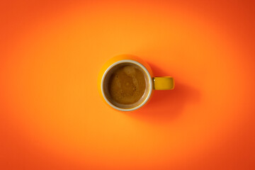Obraz na płótnie Canvas Freshly brewed mug of double espresso in the middle of bright orange background