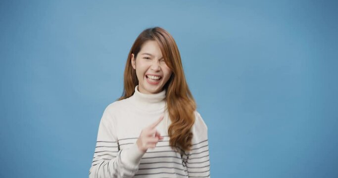 Youth attractive cheerful Asia lady wear sweater enjoy happy funny dance looking at camera and move around stand isolated over blue background. Female playful cute dance, Empty copy space concept.
