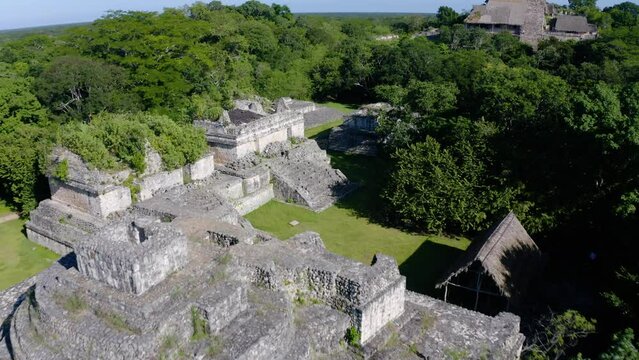 Aerial view low  over old Maya temples in EK Balam, sunny Mexico - tilt, drone shot