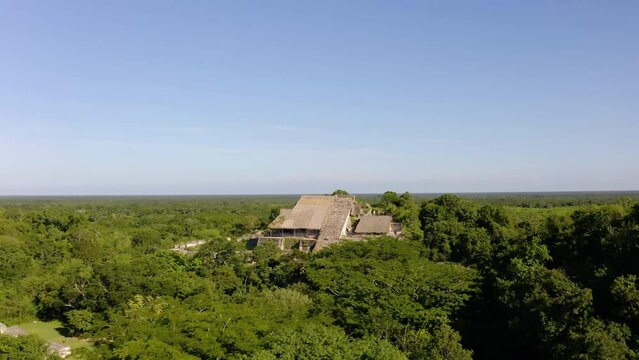 Aerial view over forest towards Zona Arqueol&oacute;gica de Ek Balam in sunny Yucatan, Mexico - tilt, drone shot
