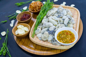 Fototapeta na wymiar Oysters with acacia leaves Fried onions, fresh garlic, seafood sauce. Popular food of Asian people