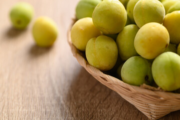 Apricot green with yellow (Japanese apricot) in basket on wooden background