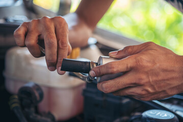 Close up Car Mechanic man hands repairing car auto repair shop. Man hands fixing machinery vehicle mechanical service. open vehicle hood checking up auto mobile. Vehicle Car maintenance engineer.