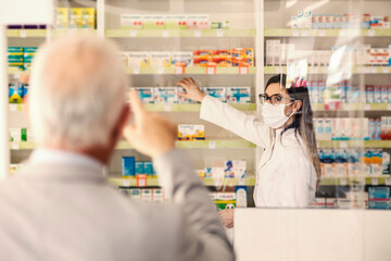 A pharmacist getting drug that old man pointing at at pharmacy.