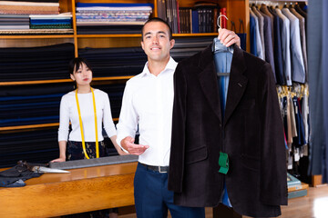 Happy man holding classic jacket in clothing store. High quality photo