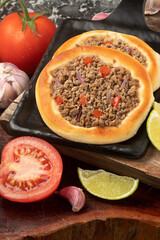 Delicious Arabian sfiha of meat on black cutting board.