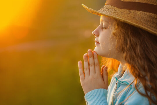 Little girl with praying in outdoors.