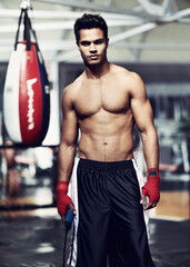 Fototapeta na wymiar Boxing is his whole life. Portrait of a handsome young boxer standing in the gym.