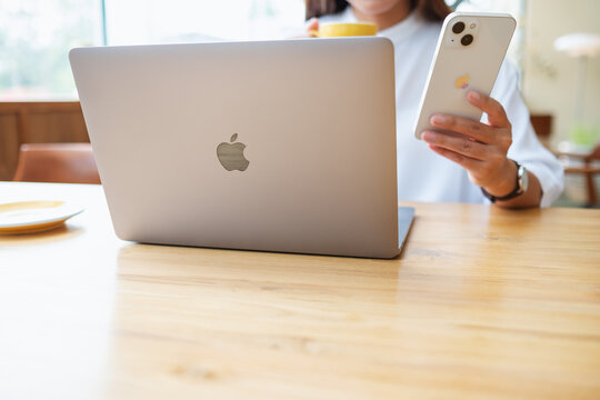 Mar 19th 2022 : A woman holding and using Iphone 13 smart phone with Apple MacBook Pro laptop computer, Chiang mai Thailand