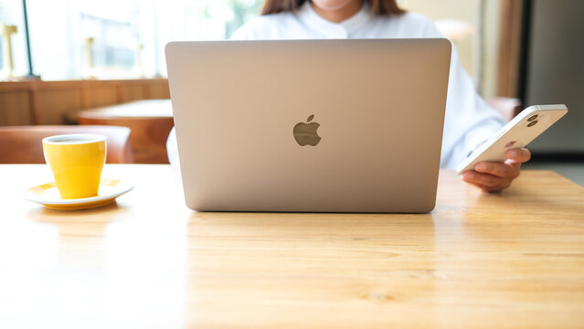 Mar 19th 2022 : A woman holding and using Iphone 13 smart phone with Apple MacBook Pro laptop computer, Chiang mai Thailand