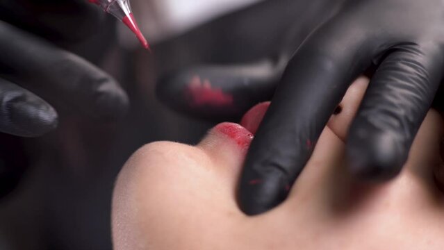 lip tattoo microblading in a permanent makeup clinic, applying coloring pigment to lips using a tattoo machine, makeup pigmentation on a woman's face close-up. Macro