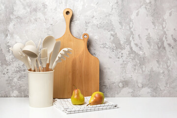 Cooking utensil set on kitchen table. Silicone kitchen tools, wooden cutting boards, mortar bowl...