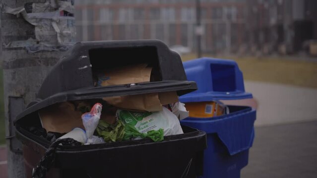 Overflowing garbage bins in city park - Climate change environmental issues with overfilled trash cans in city - full garbage in dark grey foggy city