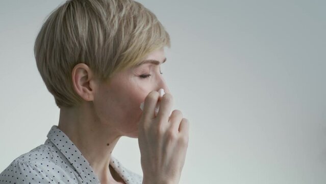 Stress and depression concept. Close up of unhappy middle aged caucasian lady crying with tissue, sitting alone at home