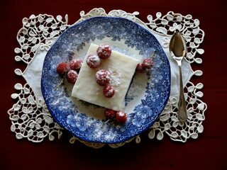 Red berries decorated white custard dessert on bleu blanc porcelain plate over handmade placemat, top view