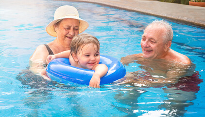 Fototapeta premium A child with a couple of seniors in the pool