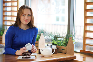 Young girl in cafe sits and drinks tea