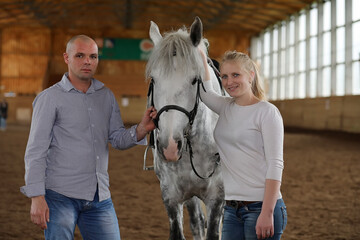 People on a horse training in a wooden arena