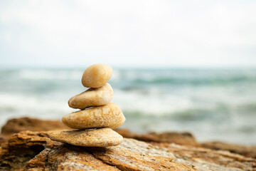 Stack Stone on sea at coast. balance and harmony pebble tower pyramid on big rock with blur wave and blue ocean. calm, meditate or aroma, vacation relax  therapy spa nature, wellness symbols concept.