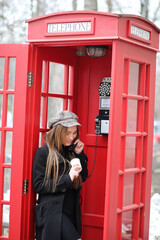 Beautiful young girl in a phone booth. The girl is talking on the phone from the payphone. English...