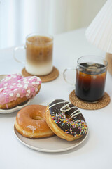 Colorful doughnut with cup of coffee on white table