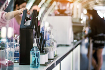 Blue alcohol gel bottle for hand cleaning to prevent the spreading of the Coronavirus (Covid-19) on counter to service for customers at cafe or coffee shop. Healthcare concept. New normal lifestyle.