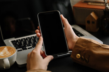 Professional businesswoman holding blank screen smartphone Isolated  in dark modern office room.
