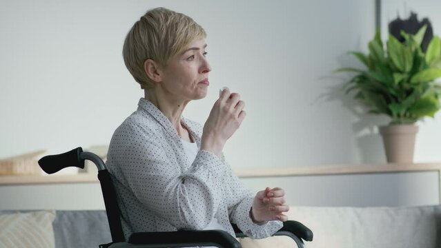 Post-traumatic depression. Unhappy middle aged woman with disability crying, sitting at home in wheelchair, empty space