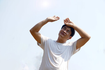 Asian middle-aged man feels hot, stands outdoor in sunny day. Concept : hot weather in summer, high...